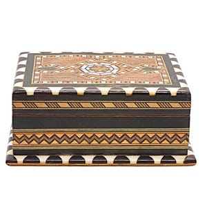 May include: A rectangular wooden box with intricate inlaid patterns. The lid features a central diamond design with a starburst, surrounded by geometric shapes in various wood tones. The sides are dark with decorative bands.