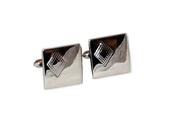 May include: A pair of silver cufflinks with a diamond-shaped design.