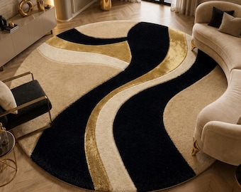 May include: A large circular area rug featuring a bold, abstract pattern of sweeping, curved lines in black, cream, and metallic gold. The rug has a textured, plush pile surface and is positioned in the center of a room with a curved sofa and chair.