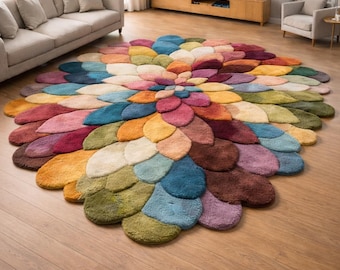 May include: A large, colorful area rug in a flower petal design. The rug features a variety of colors, including shades of blue, green, yellow, orange, pink, and brown. The rug is placed on a hardwood floor in a living room setting.