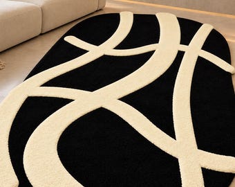 Peut inclure: Un tapis ovale avec un fond noir uni et des lignes épaisses en relief de couleur crème qui se courbent et s'entrecroisent sur la surface. Le tapis présente un poil touffu et texturé et est posé sur un sol lisse de couleur claire.