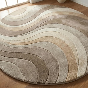 May include: A round rug with a wave pattern in shades of beige, tan, and brown. The rug has a soft, plush texture and is designed with a flowing, curved pattern. The rug is placed on a wooden floor.