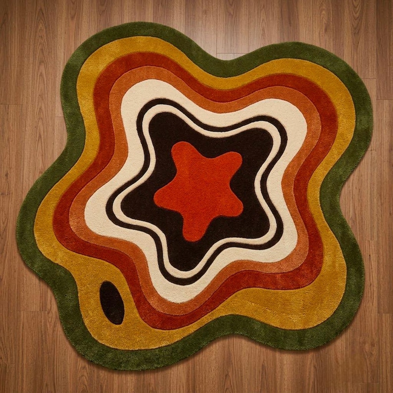 Puede incluir: Una alfombra de forma irregular similar a una ameba con capas conc&eacute;ntricas y onduladas. La paleta incluye tonos verde oscuro, amarillo mostaza, naranja quemado, crema y marr&oacute;n oscuro, con una forma de estrella naranja en el centro.