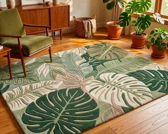Peut inclure: Un tapis rectangulaire orné d'un motif botanique à grande échelle composé de feuilles de monstera et de palmes superposées dans des tons de vert sauge, vert forêt et crème. Le tapis présente une texture touffetée avec des nervures marquées.