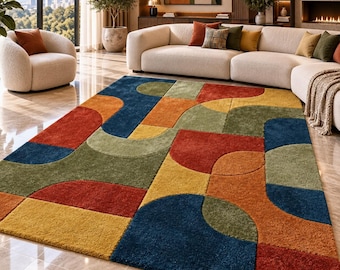 May include: A rectangular area rug featuring a geometric pattern of interlocking semicircles and rectangles in shades of deep blue, mustard yellow, olive green, and burnt orange. The rug has a thick, textured pile and covers a polished floor.