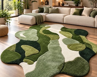 May include: An irregular, organic-shaped area rug featuring a tufted, high-pile texture. The design consists of abstract, flowing patches in various shades of forest green, sage green, olive, and cream, creating a layered, multi-tonal appearance.