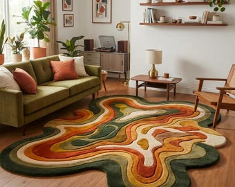 Peut inclure: Un tapis de forme organique irrégulière présentant un motif inspiré de la topographie, composé de bandes concentriques vert forêt profond, orange brûlé, jaune moutarde et crème, créant une surface texturée sur un parquet en bois.