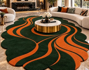 Peut inclure: Un tapis ovale au fond vert forêt profond orné de rayures orange fluides et courbes. Le tapis présente un bord festonné et est placé sur un sol en marbre poli sous une table basse ronde dotée d'une base dorée.