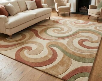 May include: A large area rug with a cream-colored background and a swirling pattern in shades of brown, red, and green. The rug is placed on a hardwood floor in a living room setting, with a sofa and chairs visible in the background.