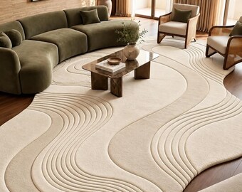 Peut inclure: Un tapis de sol crème de forme irrégulière présentant un motif sculpté et texturé de lignes ondulées fluides imitant des ondulations organiques. Le tapis possède un poil doux et une grande forme asymétrique couvrant une large surface au sol.
