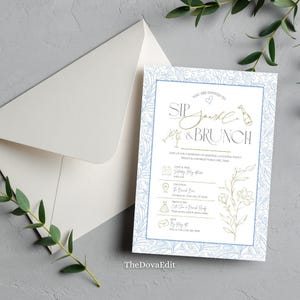May include: A brunch invitation with the text "Sip, Sparkle & Brunch". The design includes a white background, a blue floral border, and gold details. A white envelope and sprigs of greenery are also visible.