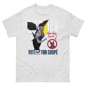 May include: Light grey t-shirt featuring a graphic of a woman in a superhero costume with the text "BIOTCH" and "VOTE FOR COUPÉ". The design includes a "This Guy Sucks" speech bubble and a no-symbol over a cat.