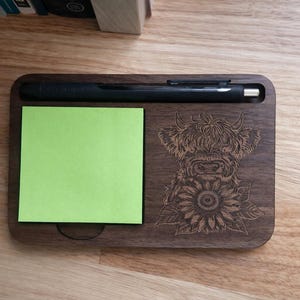 Puede incluir: Organizador de escritorio de madera oscura con ranura para bol&iacute;grafo, bloc de notas adhesivas verdes y dise&ntilde;o grabado con l&aacute;ser de una vaca de las Tierras Altas con un girasol.