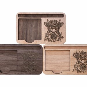 Puede incluir: Tres organizadores de escritorio rectangulares de madera con un dise&ntilde;o grabado a l&aacute;ser de una vaca Highland y un girasol. Cada organizador incluye una ranura horizontal y un compartimento cuadrado con una muesca.