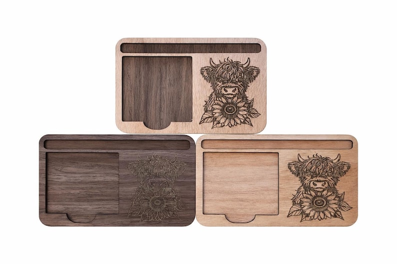 Puede incluir: Tres organizadores de escritorio rectangulares de madera con un dise&ntilde;o grabado a l&aacute;ser de una vaca Highland y un girasol. Cada organizador incluye una ranura horizontal y un compartimento cuadrado con una muesca.