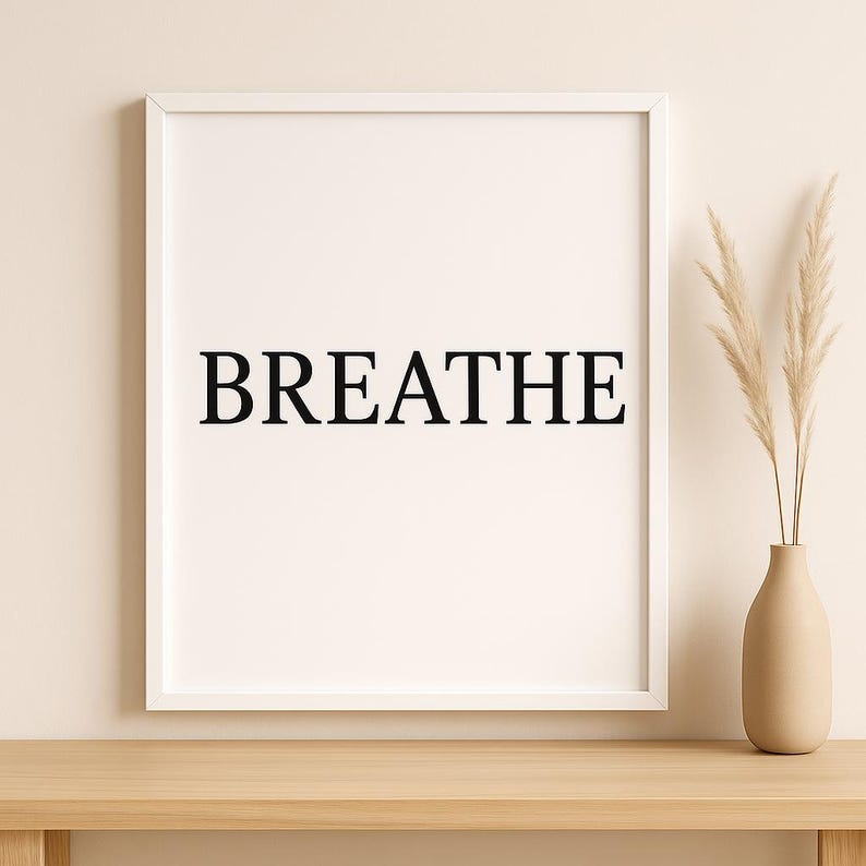 Puede incluir: Impresi&oacute;n enmarcada en blanco con la palabra "BREATHE" en negro centrada. A la derecha, un jarr&oacute;n beige con plantas secas. Todo sobre una superficie de madera.