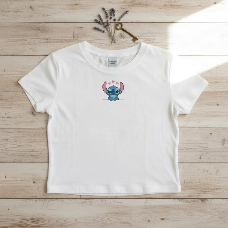 Puede incluir: Camiseta blanca con un bordado del personaje Stitch y corazones rosas. La camiseta de manga corta tiene cuello redondo y est&aacute; hecha de un material suave y ligero. El dise&ntilde;o est&aacute; centrado en el pecho.
