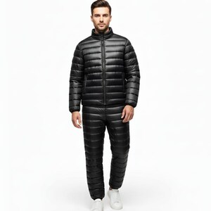 May include: A black, quilted, zip-up jacket and matching pants set. The jacket has a stand-up collar and the pants are straight-legged. The person is wearing white sneakers. The outfit is designed for cold weather.