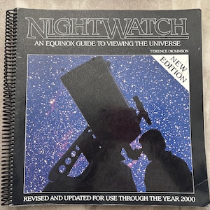 Op de afbeelding: Een spiraalgebonden boek getiteld "NIGHTWATCH" met de ondertitel "AN EQUINOX GUIDE TO VIEWING THE UNIVERSE" door Terence Dickinson. De omslag toont een zwart silhouet van een telescoop en een persoon die een sterrenhemel observeert. Een "NEW EDITION" sticker is zichtbaar.