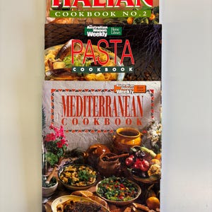 Könnte beinhalten: Drei Kochbücher übereinander gestapelt. Das oberste Buch trägt den Titel "ITALIAN COOKBOOK NO.2". Das mittlere Buch heißt "PASTA COOKBOOK". Das untere Buch ist "MEDITERRANEAN COOKBOOK" mit Essensbildern. Alle aus der Reihe "Australian Women's Weekly".