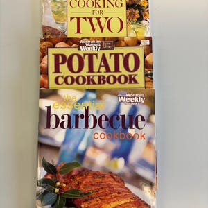 Peut inclure: Trois livres de cuisine empilés. Le livre du haut est intitulé "Cooking for Two". Le livre du milieu est intitulé "Potato Cookbook". Le livre du bas est intitulé "Essential Barbecue Cookbook".