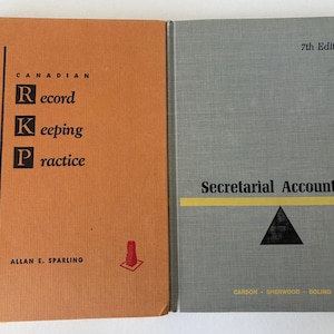 Peut inclure: Deux manuels à couverture rigide placés côte à côte. Le livre de gauche est orange avec le titre Canadian Record Keeping Practice par Allan E. Sparling. Le livre de droite est gris avec le titre Secretarial Accounting 7th Edition par Carson, Sherwood, Boling.