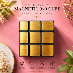 May include: A black and gold magnetic 3x3 cube with the text "PREMIUM MAGNETIC 3x3 CUBE". The cube has gold-colored squares with a brushed metal texture. The background is pink with decorative elements.
