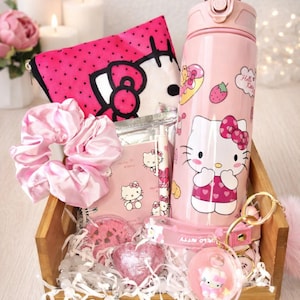 May include: A wooden crate filled with pink Hello Kitty themed items. Includes a water bottle, cosmetic bag, scrunchie, stationery, bath bombs, and a keychain. The water bottle has a Hello Kitty graphic and is approximately 25 cm tall.