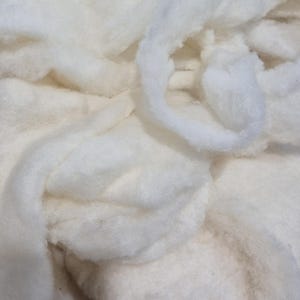 Könnte beinhalten: Nahaufnahme von weicher, weißer Baumwollwatte. Das Bild zeigt einen Haufen flauschigen, wolkenartigen Materials mit unterschiedlichen Texturen und Tiefen. Die Baumwolle erscheint sauber und einsatzbereit für Bastelarbeiten oder andere Projekte.