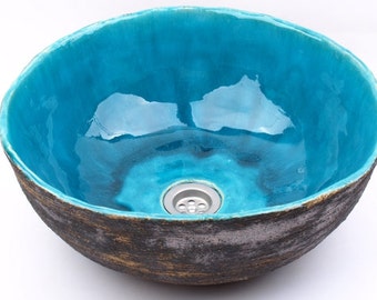 May include: A turquoise ceramic sink with a rough, textured exterior and a smooth, glossy interior. The sink has a round shape and a small drain in the centre.