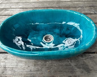 May include: A teal blue oval ceramic sink with a silver drain.