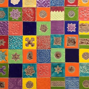 Pode incluir: Uma arte de parede de mosaico de azulejos coloridos com uma variedade de padrões geométricos e florais. Os azulejos são dispostos em um padrão de grade e são feitos de cerâmica. As cores incluem vermelho, azul, verde, amarelo, laranja, roxo e branco.