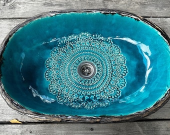 Puede incluir: Un lavabo de cerámica turquesa con un diseño de mandala decorativo y un desagüe redondo.
