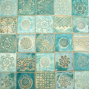 Puede incluir: Un conjunto de 16 azulejos de cerámica azul turquesa con varios patrones en relieve de color beige claro. Los azulejos presentan una variedad de diseños florales y geométricos.