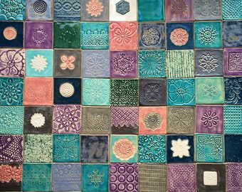 May include: A colourful mosaic tile wall art featuring a variety of patterns and designs. The tiles are arranged in a grid pattern and are made of ceramic. The tiles are in shades of blue, green, purple, pink, and white.