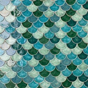 Può includere: Primo piano di una parete rivestita di piastrelle in ceramica blu, verde e turchese disposte a forma di squame di pesce.