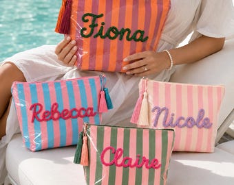 May include: Four rectangular zippered pouches with vertical stripes in orange and pink, blue and pink, light pink and white, and green and pink. Each pouch features a name in cursive rope lettering: Fiona, Rebecca, Nicole, and Claire.
