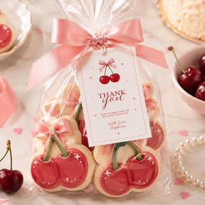 May include: A clear plastic bag containing cherry-shaped sugar cookies with pink icing bows, tied with a pink satin ribbon and a white tag that reads "THANK YOU FOR CELEBRATING MY BIRTHDAY WITH ME! WITH LOVE, STEPHANIE" with a cherry illustration.