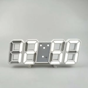 May include: A white digital LED clock with a rectangular frame and large, hollow block-style numeric displays. The center panel features small circular indicator lights labeled PM, AL, and TEMP, with a light gray finish and two small support stands.