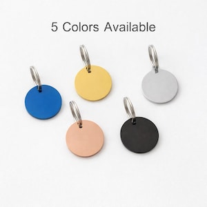 May include: Five circular metal tags with attached split rings, presented in blue, gold, silver, rose gold, and black finishes. The text 5 Colors Available is displayed at the top, indicating the variety of options for these small, flat, round charms.