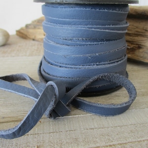 May include: A spool of dark blue leather cord. The cord is wound tightly around the spool and is ready to be used for crafting projects.