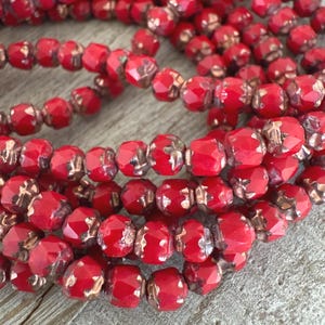 May include: Close-up of strands of faceted red beads with metallic gold accents. The beads are strung together, creating a textured and colorful display. These beads are suitable for jewelry making or craft projects.