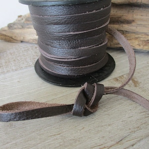 May include: A spool of brown leather cord, with a length of cord tied in a knot.