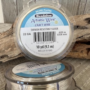 May include: A spool of silver-plated tarnish resistant Artistic Wire, 22 gauge, 10 yards (9.1 metres) in length. The label reads "Beadalon Artistic Wire Craft Wire".
