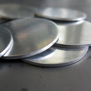 May include: A stack of silver metal discs, likely used for crafting or industrial purposes.