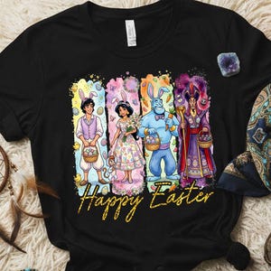 May include: Black t-shirt featuring a colorful graphic with Disney characters dressed for Easter, holding baskets and eggs. The words "Happy Easter" are written in gold script below the characters. The shirt is displayed on a cream-colored, textured surface.