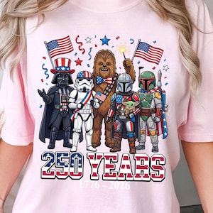 May include: Pink t-shirt featuring a graphic of Star Wars characters, including Darth Vader, a Stormtrooper, Chewbacca, and others, holding American flags. The text "250 YEARS 1776-2026" is printed below the characters.
