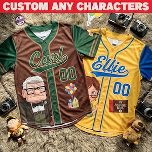 May include: Two baseball jerseys, one brown and green, the other yellow and blue. The brown jersey features the name "Carl" and a cartoon image. The yellow jersey has "Ellie" and a cartoon image. Both have the number "00" on them. The text "CUSTOM ANY CHARACTERS" is at the top.