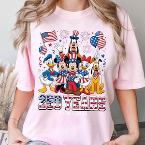 May include: Pink t-shirt featuring a graphic of Disney characters Mickey Mouse, Minnie Mouse, Donald Duck, Daisy Duck, Goofy, and Pluto, dressed in patriotic attire. The shirt includes the text "250 YEARS" and the dates "1776-2026".