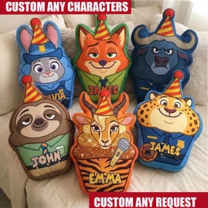 May include: Six custom-shaped plush pillows featuring cartoon animal characters wearing party hats. The characters include a rabbit, fox, buffalo, sloth, gazelle, and cheetah, with some pillows displaying names like Olivia, James, John, and Emma.